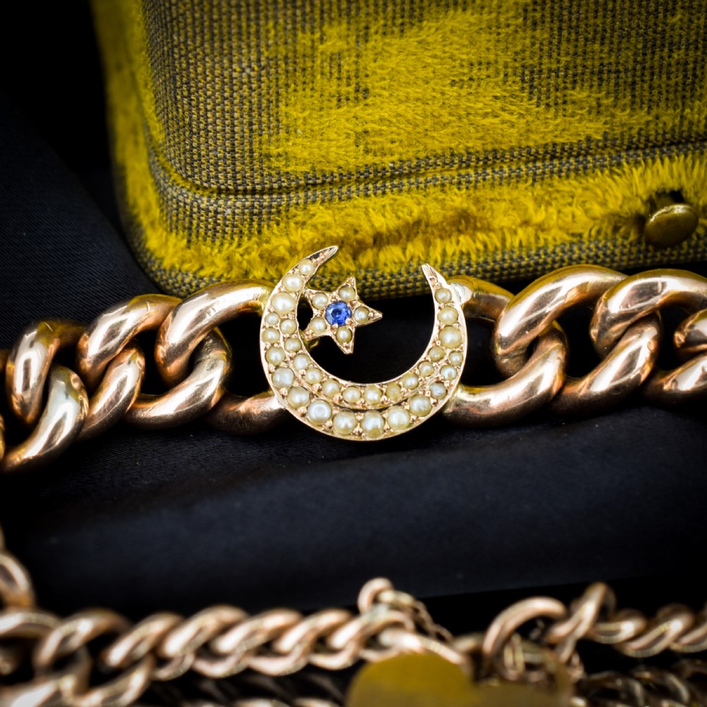An antique 9ct rose gold curb chain bracelet featuring a heart padlock clasp and a central crescent moon and star motif set with seed pearls. View V
