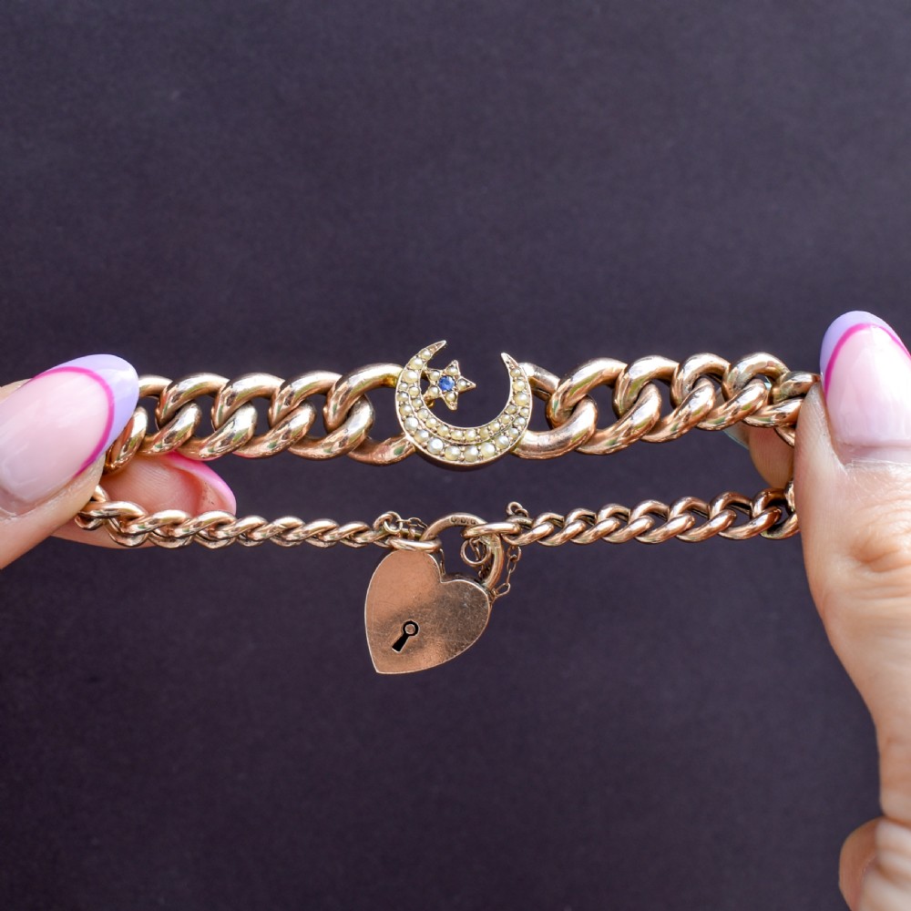 An antique 9ct rose gold curb chain bracelet featuring a heart padlock clasp and a central crescent moon and star motif set with seed pearls. View VIII