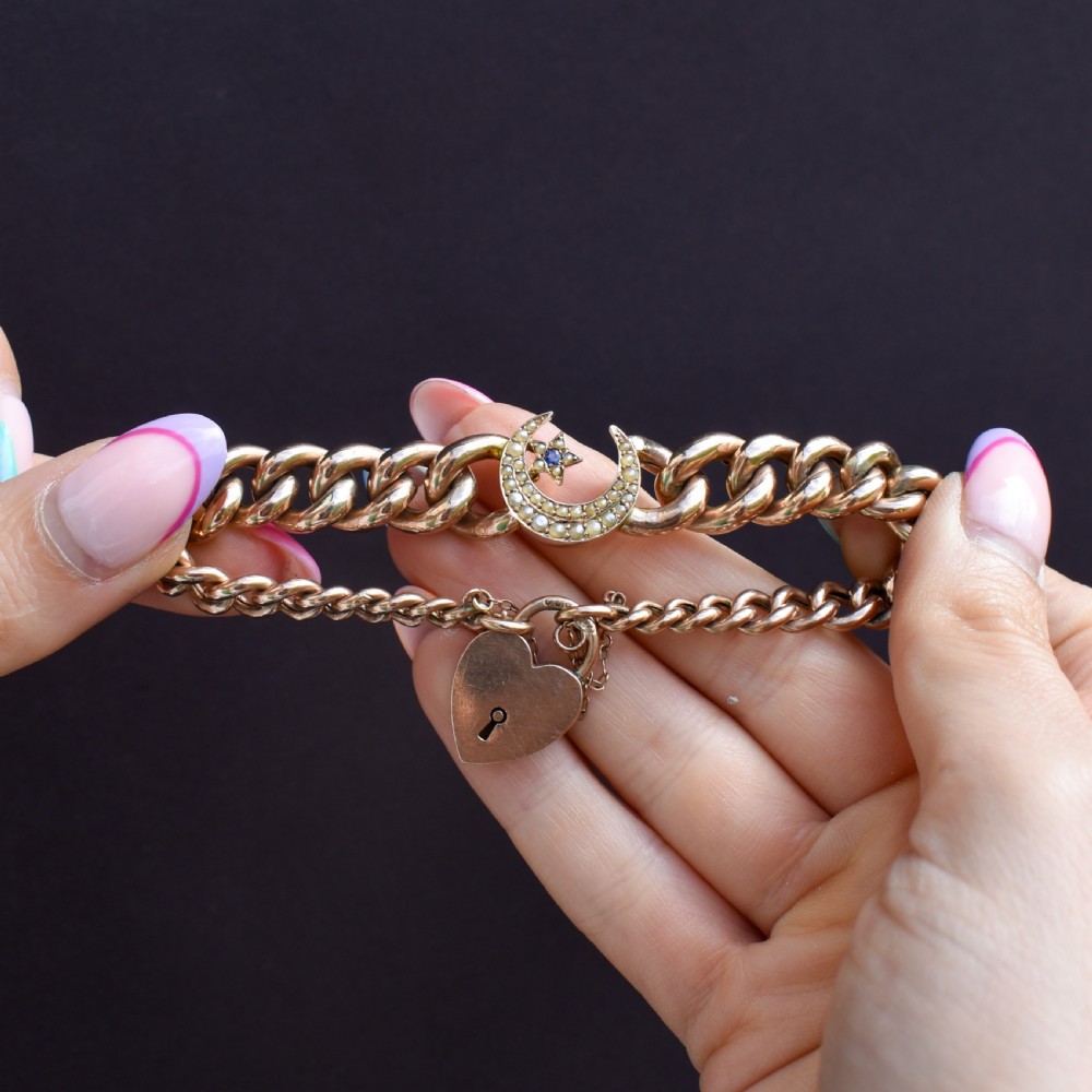 An antique 9ct rose gold curb chain bracelet featuring a heart padlock clasp and a central crescent moon and star motif set with seed pearls. View IX