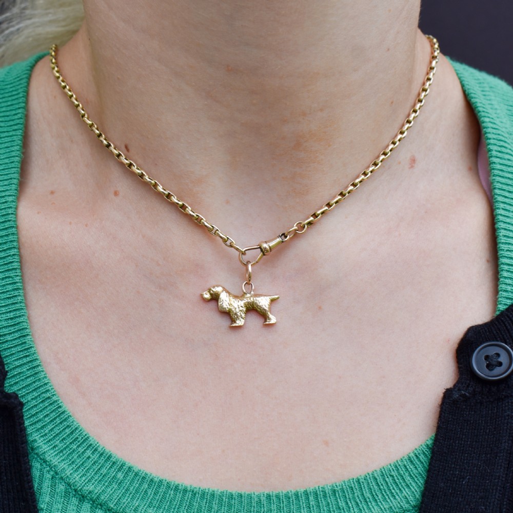 A small 9ct yellow gold charm cast in the detailed shape of a standing spaniel dog with a textured coat and an attached jump ring. View III