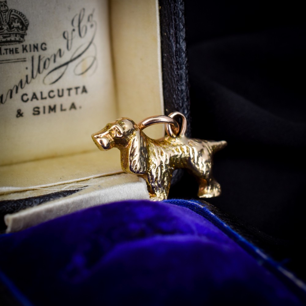 A small 9ct yellow gold charm cast in the detailed shape of a standing spaniel dog with a textured coat and an attached jump ring. View V