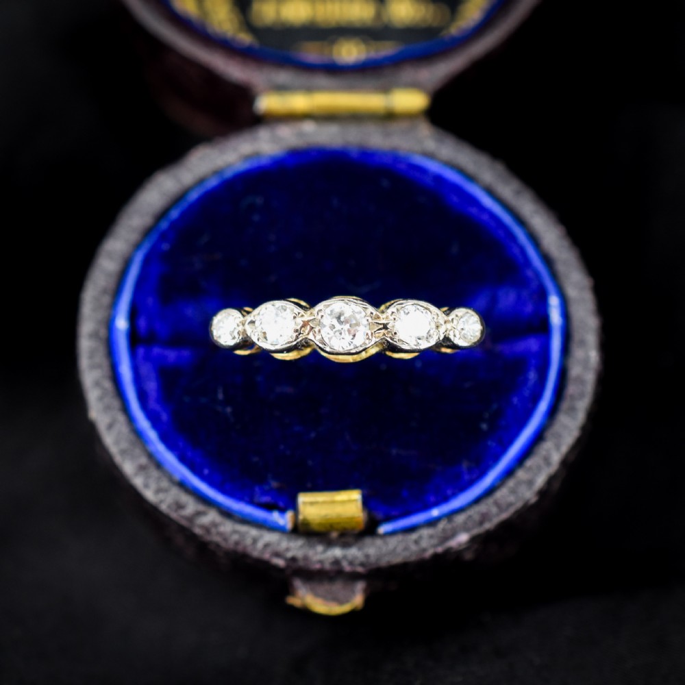 An antique 18ct yellow gold ring set with five round diamonds arranged horizontally in a row across the band.