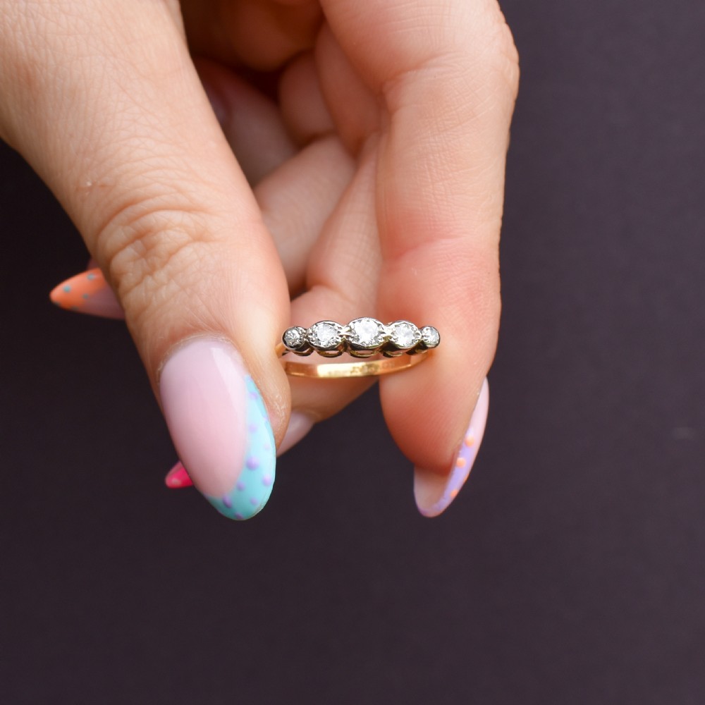 An antique 18ct yellow gold ring set with five round diamonds arranged horizontally in a row across the band. View II