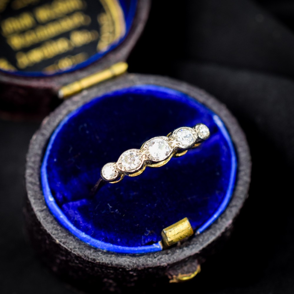 An antique 18ct yellow gold ring set with five round diamonds arranged horizontally in a row across the band. View IV