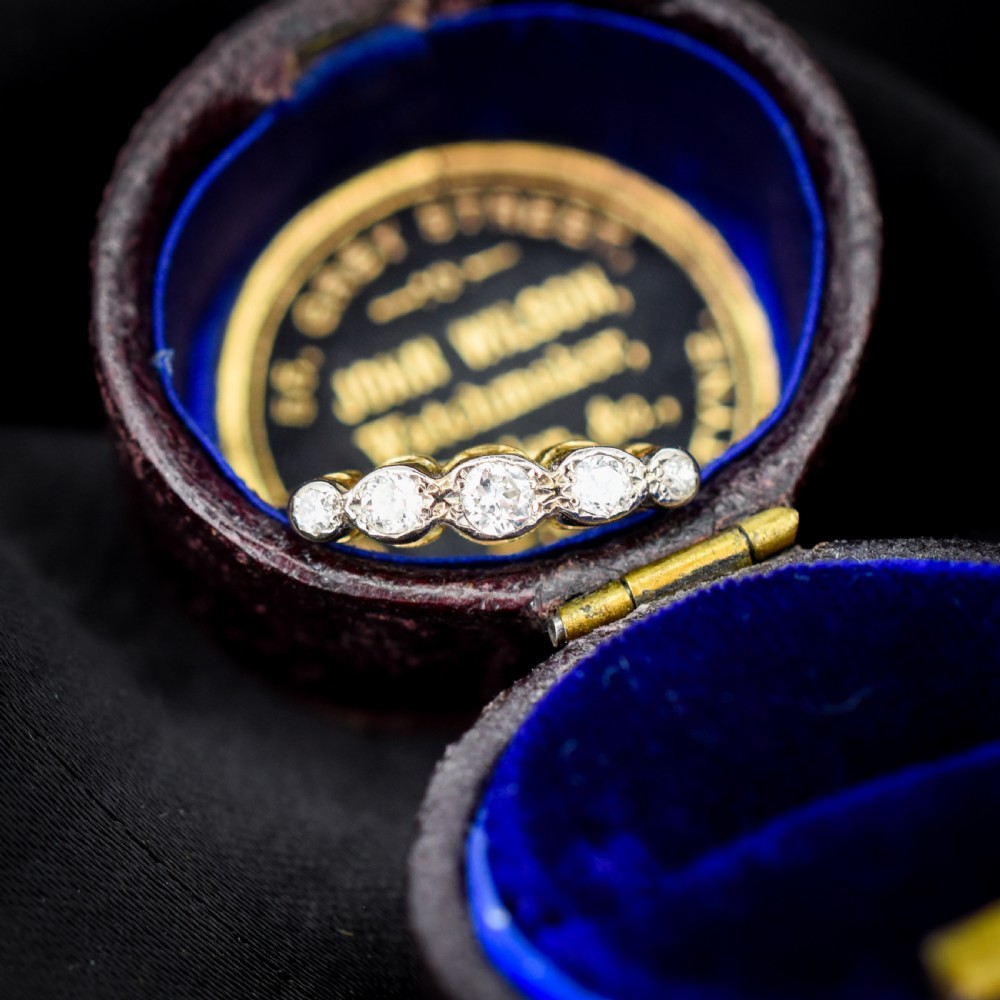 An antique 18ct yellow gold ring set with five round diamonds arranged horizontally in a row across the band. View V