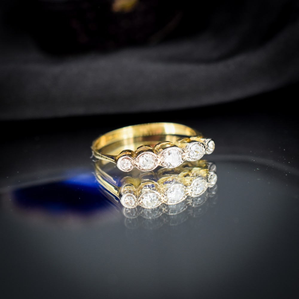 An antique 18ct yellow gold ring set with five round diamonds arranged horizontally in a row across the band. View VI