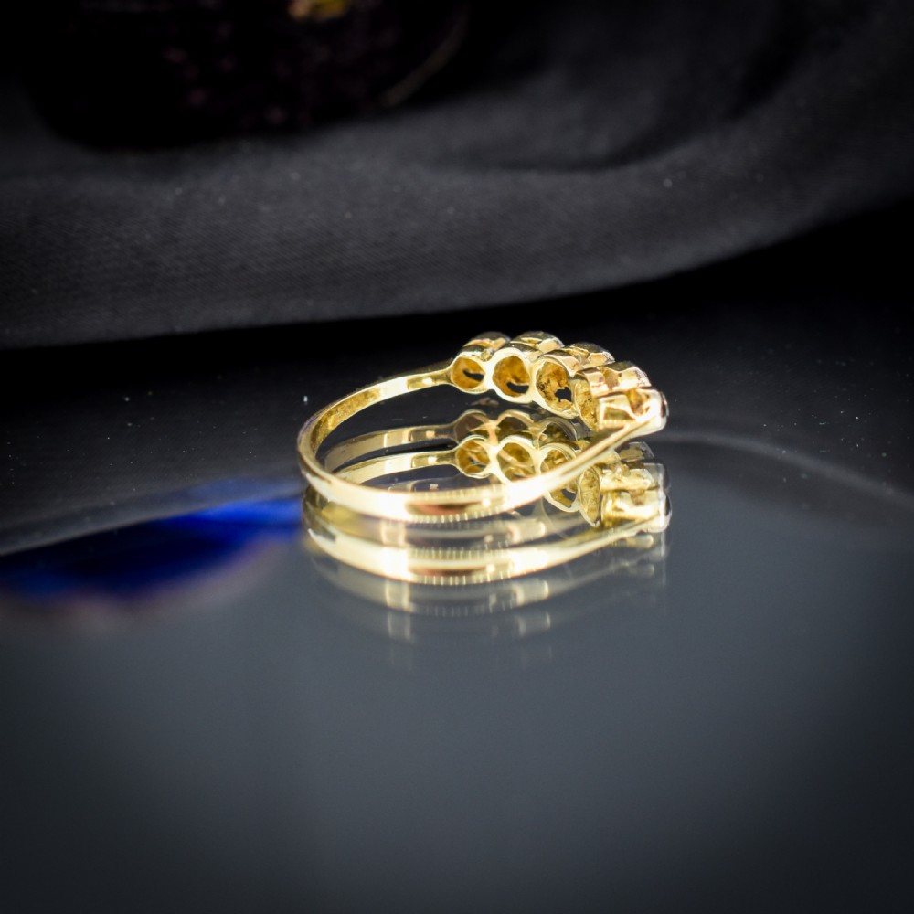An antique 18ct yellow gold ring set with five round diamonds arranged horizontally in a row across the band. View VII