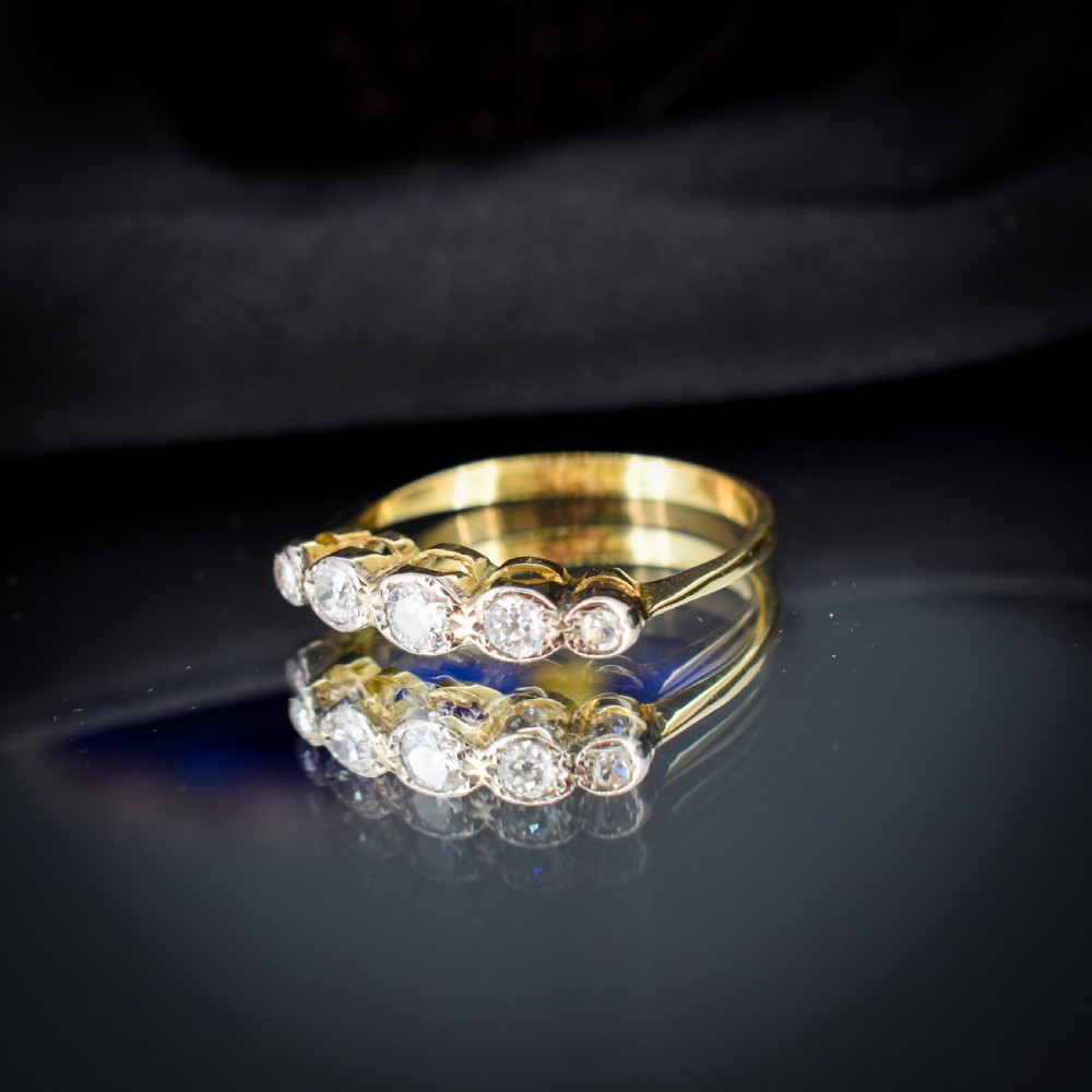 An antique 18ct yellow gold ring set with five round diamonds arranged horizontally in a row across the band. View IX