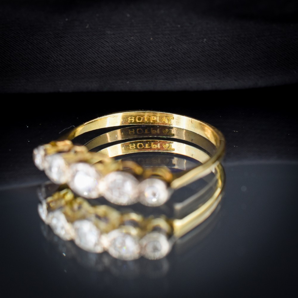 An antique 18ct yellow gold ring set with five round diamonds arranged horizontally in a row across the band. View X