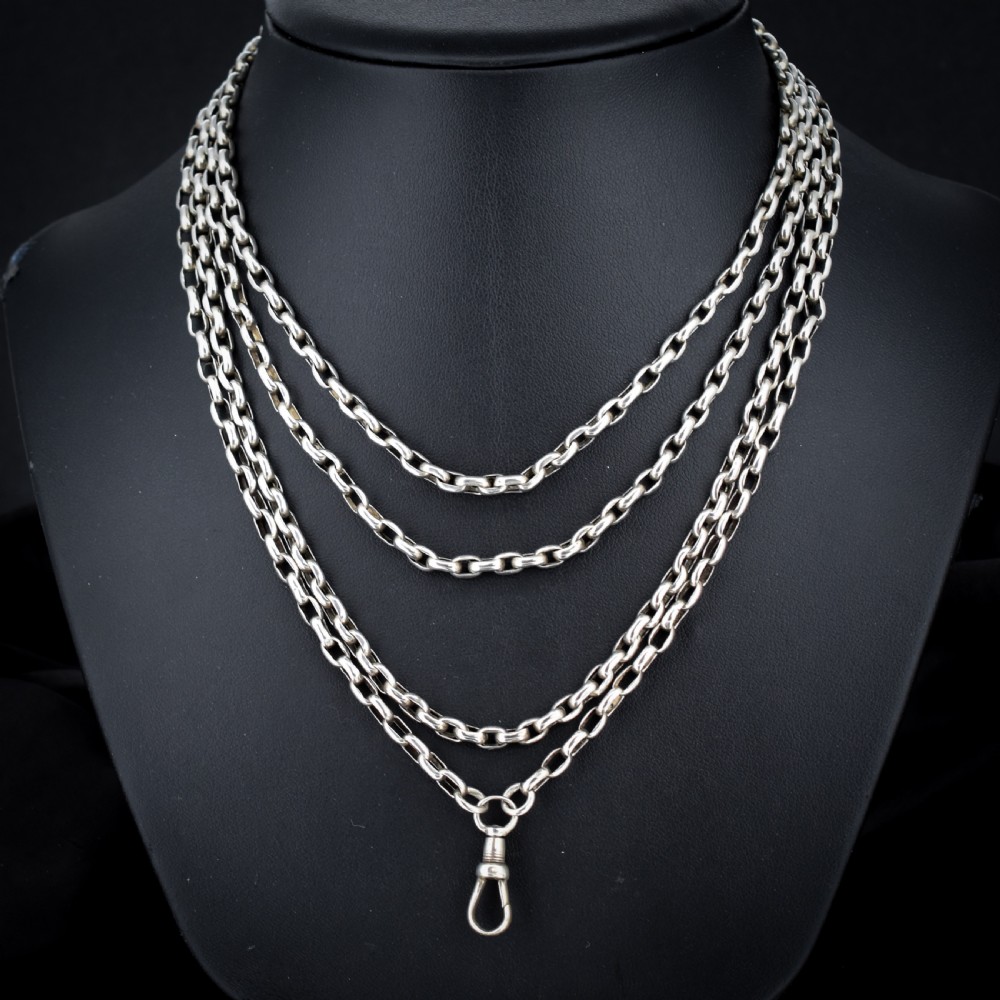 An antique silver long guard chain with belcher links coiled neatly inside a royal blue velvet presentation box fitted with a dog clip clasp. View II