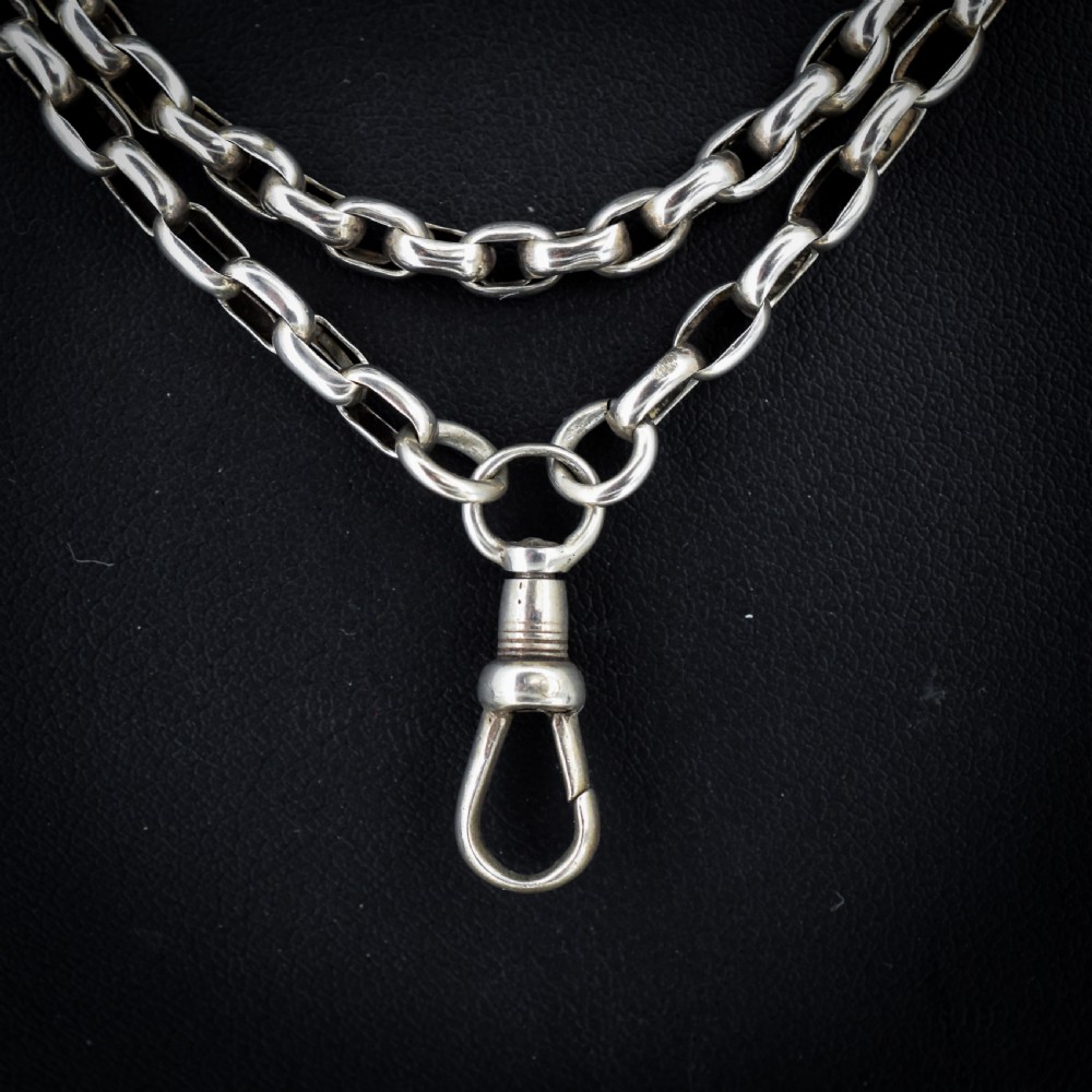 An antique silver long guard chain with belcher links coiled neatly inside a royal blue velvet presentation box fitted with a dog clip clasp. View III