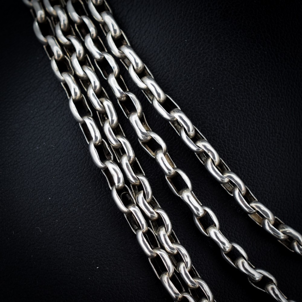 An antique silver long guard chain with belcher links coiled neatly inside a royal blue velvet presentation box fitted with a dog clip clasp. View IV