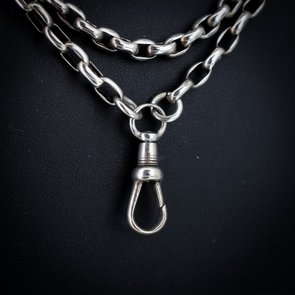 An antique silver long guard chain with belcher links coiled neatly inside a royal blue velvet presentation box fitted with a dog clip clasp. View V