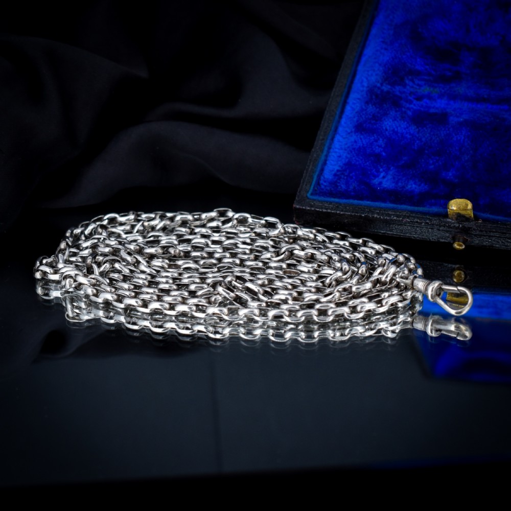 An antique silver long guard chain with belcher links coiled neatly inside a royal blue velvet presentation box fitted with a dog clip clasp. View VII