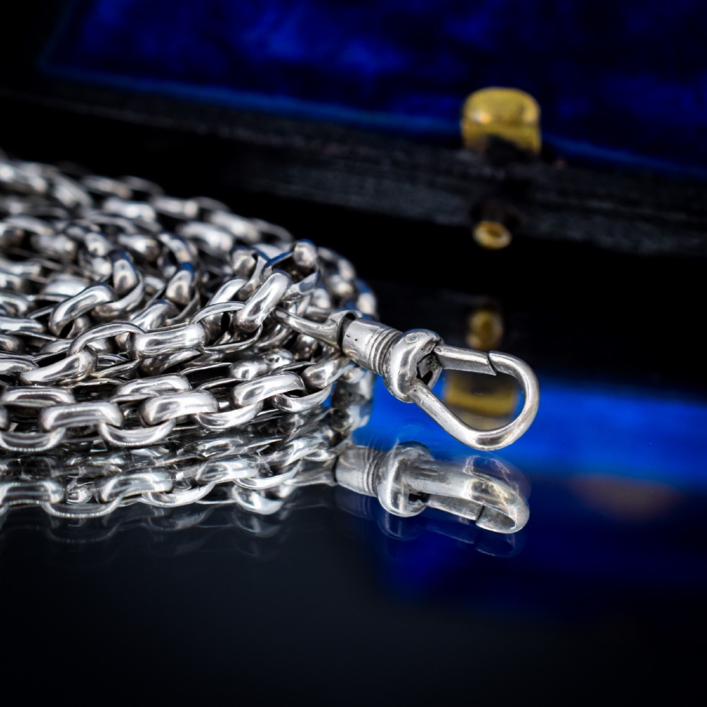 An antique silver long guard chain with belcher links coiled neatly inside a royal blue velvet presentation box fitted with a dog clip clasp. View VIII