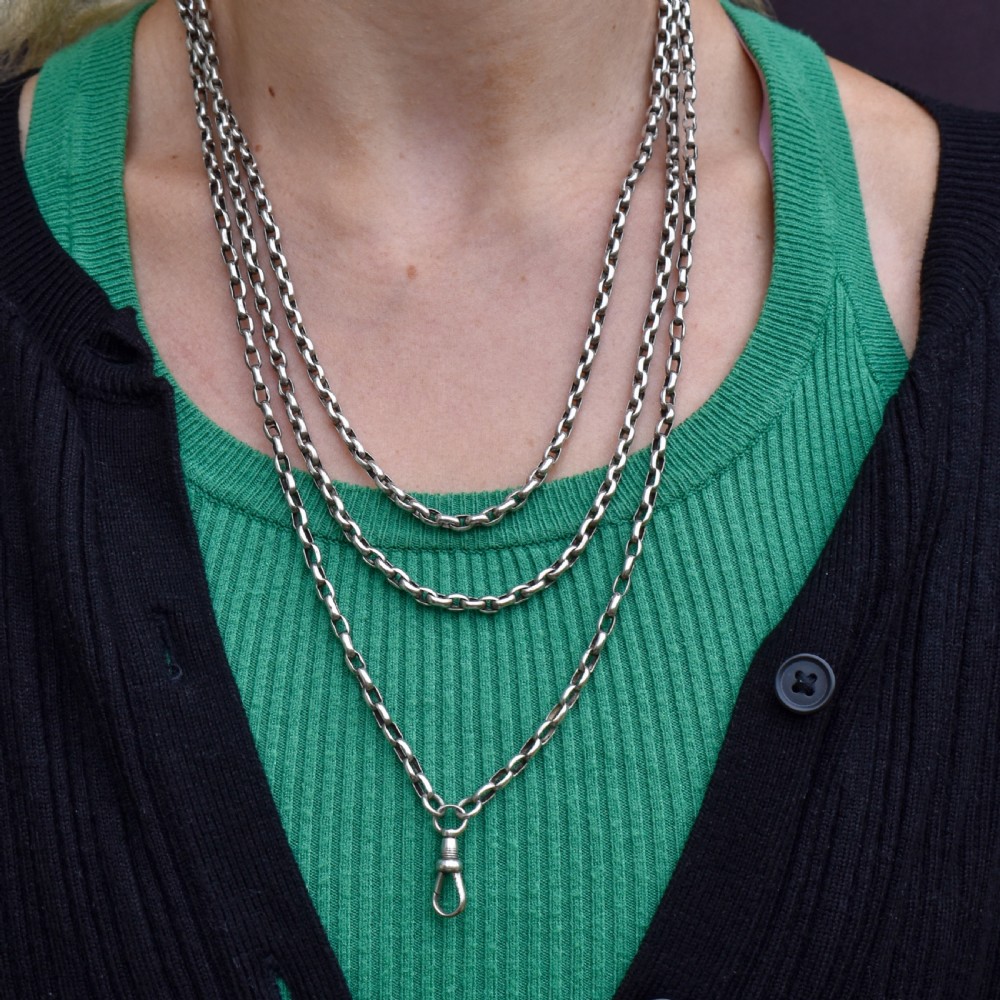 An antique silver long guard chain with belcher links coiled neatly inside a royal blue velvet presentation box fitted with a dog clip clasp. View IX