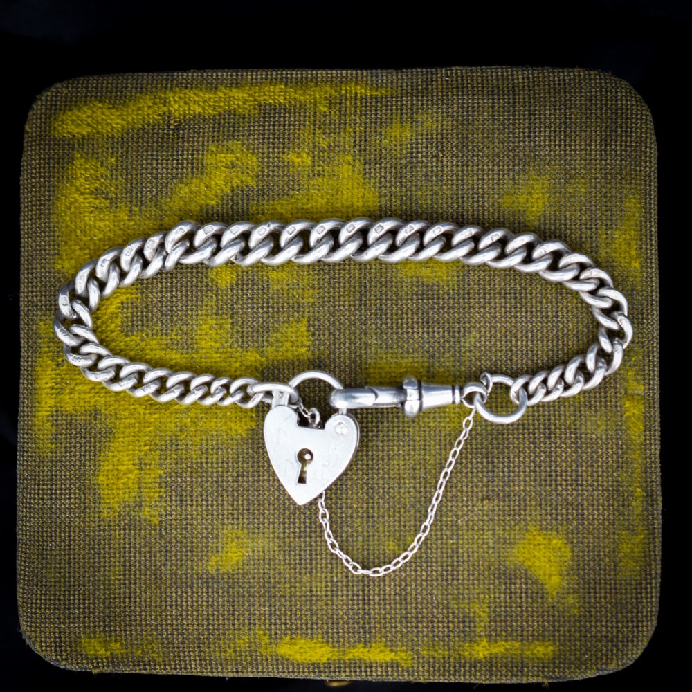 An antique sterling silver graduated curb link bracelet featuring a heart-shaped padlock clasp, safety chain, and a swivel dog clip attachment.