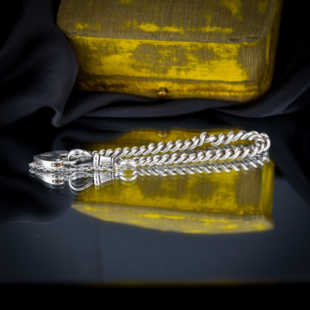 An antique sterling silver graduated curb link bracelet featuring a heart-shaped padlock clasp, safety chain, and a swivel dog clip attachment. View IV
