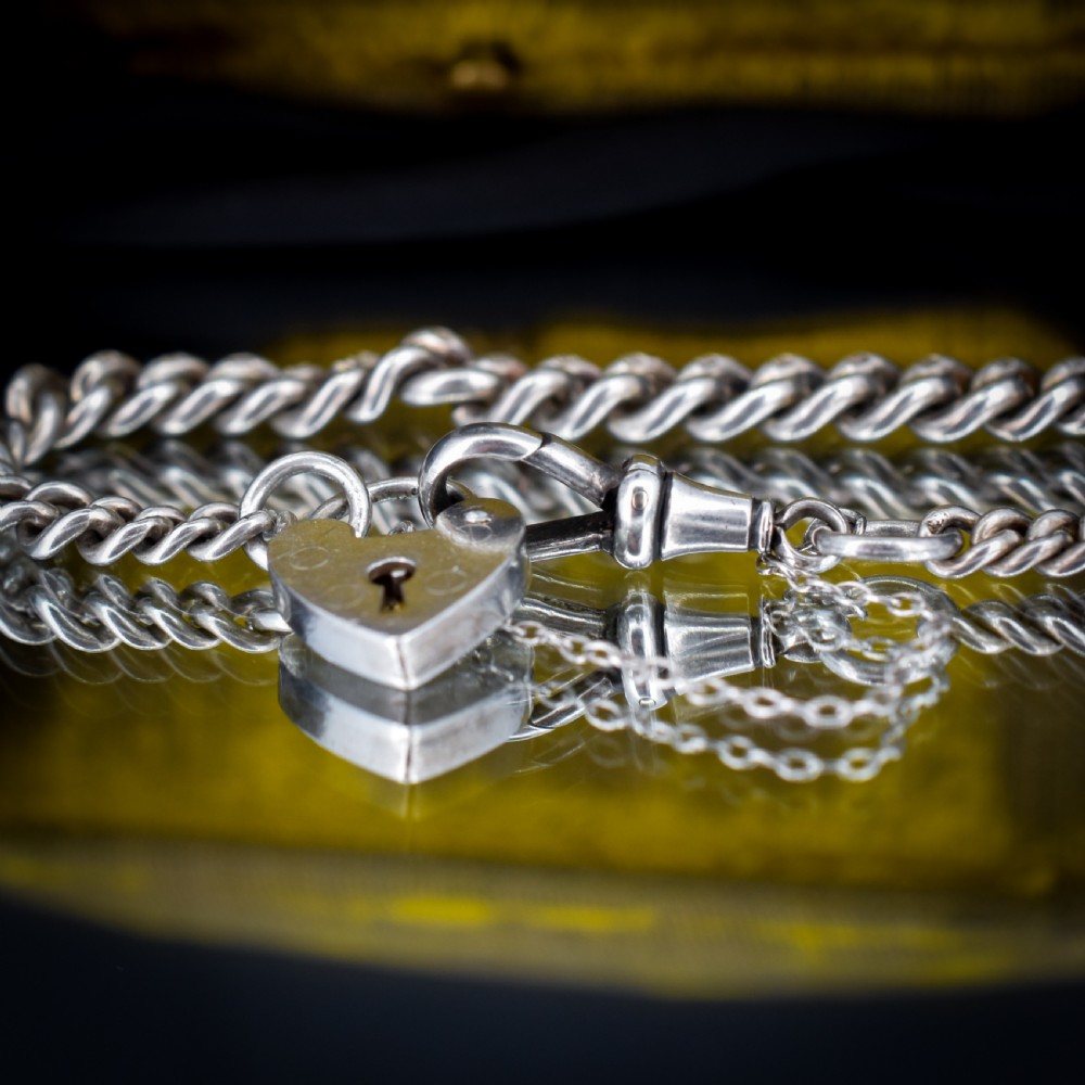 An antique sterling silver graduated curb link bracelet featuring a heart-shaped padlock clasp, safety chain, and a swivel dog clip attachment. View V
