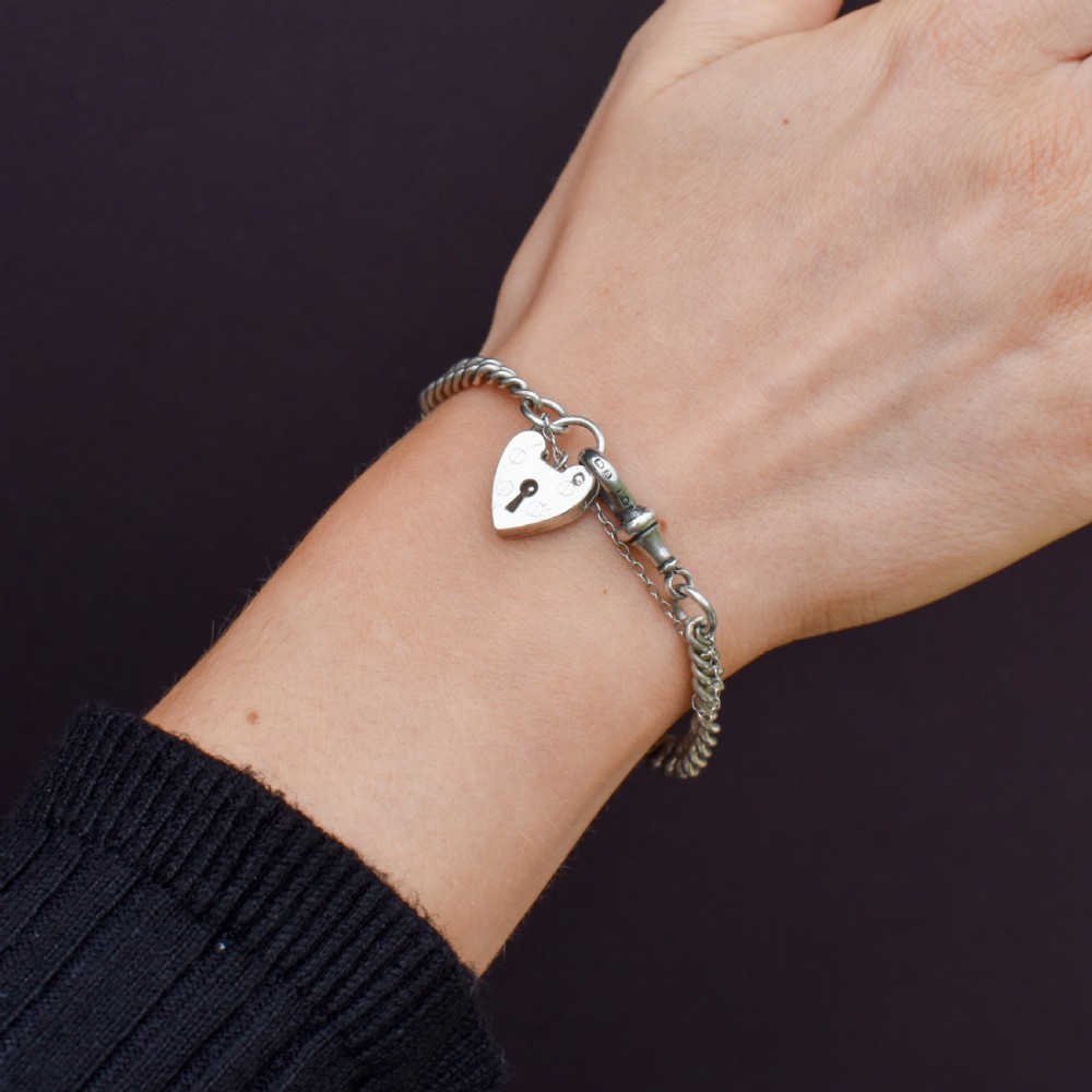 An antique sterling silver graduated curb link bracelet featuring a heart-shaped padlock clasp, safety chain, and a swivel dog clip attachment. View VIII