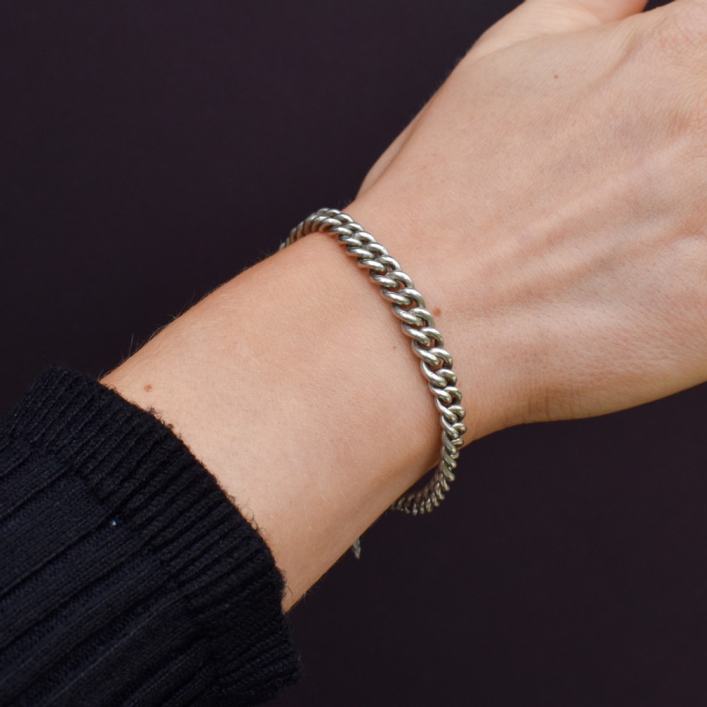 An antique sterling silver graduated curb link bracelet featuring a heart-shaped padlock clasp, safety chain, and a swivel dog clip attachment. View IX
