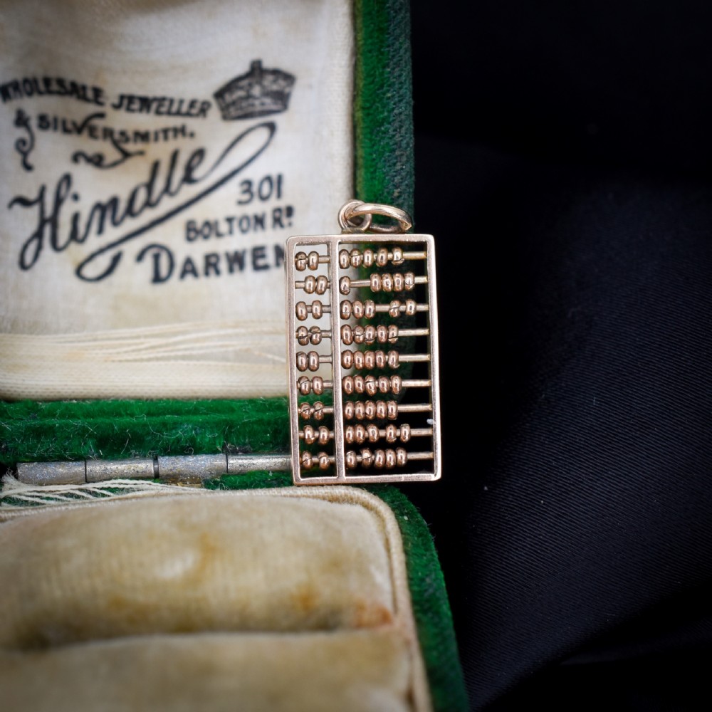 A miniature rectangular 14ct yellow gold abacus charm featuring multiple rows of small gold beads framed with a top suspension ring.