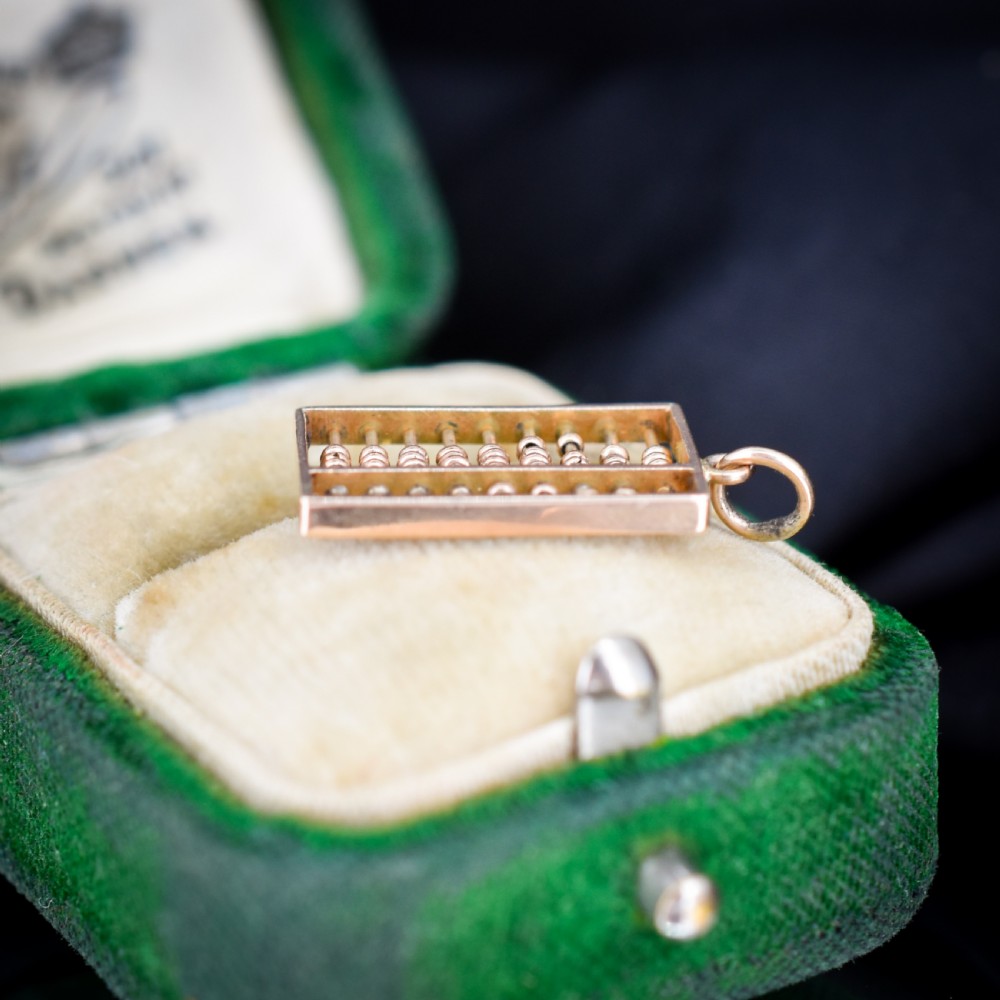 A miniature rectangular 14ct yellow gold abacus charm featuring multiple rows of small gold beads framed with a top suspension ring. View III