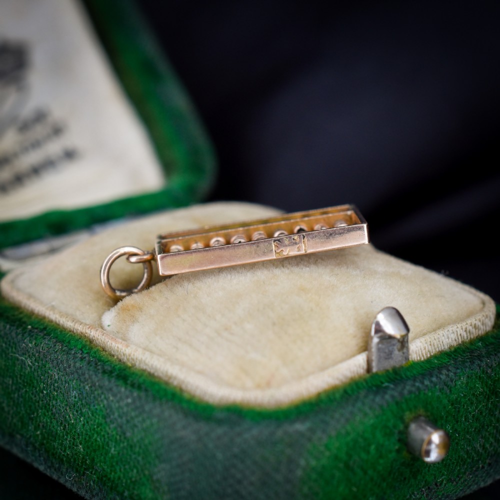 A miniature rectangular 14ct yellow gold abacus charm featuring multiple rows of small gold beads framed with a top suspension ring. View IV