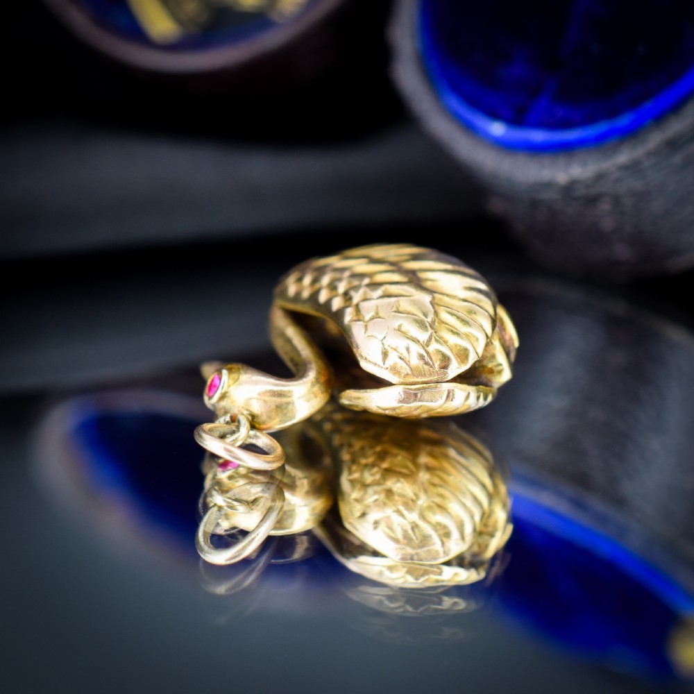A small 9ct yellow gold swan charm featuring textured feather details, a round ruby set as the eye, and visible hallmarks stamped on the side. View V