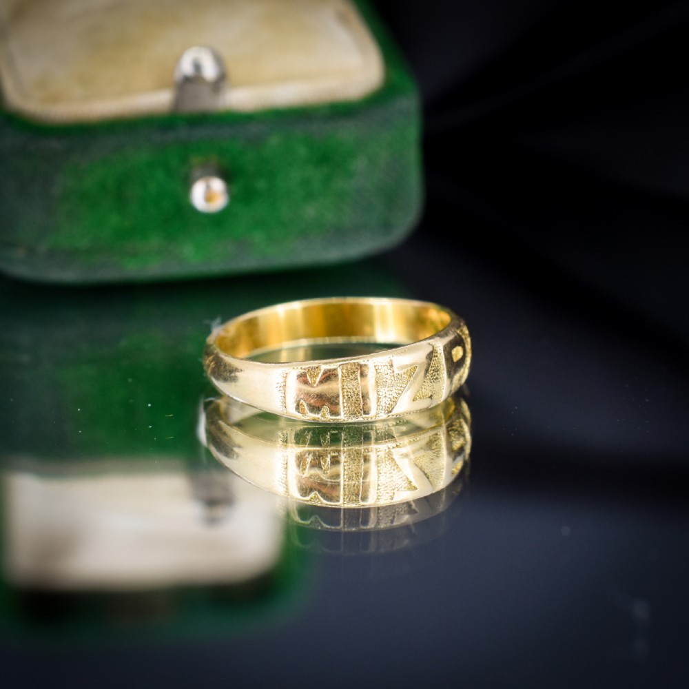 An antique 18ct yellow gold band ring featuring the word MIZPAH in raised capital lettering against a stippled textured background. View III