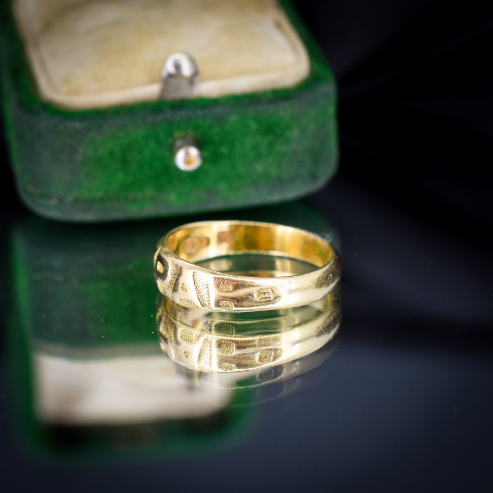 An antique 18ct yellow gold band ring featuring the word MIZPAH in raised capital lettering against a stippled textured background. View V
