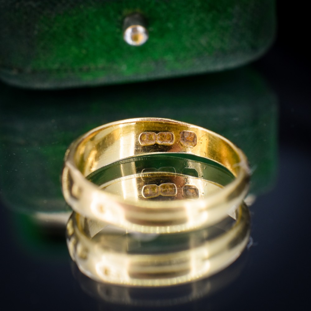 An antique 18ct yellow gold band ring featuring the word MIZPAH in raised capital lettering against a stippled textured background. View VI