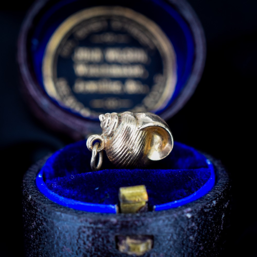 A small three-dimensional 9ct yellow gold seashell charm with ribbed texturing and a top suspension ring.