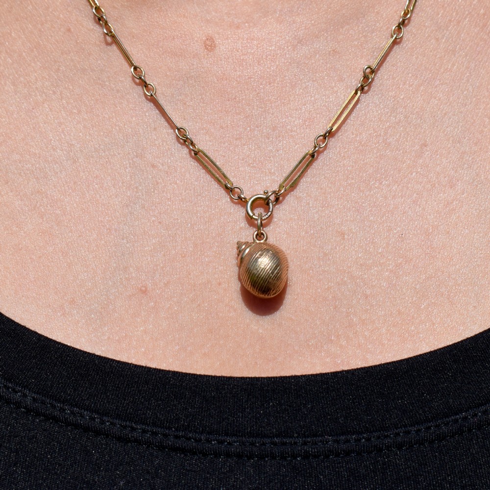 A small three-dimensional 9ct yellow gold seashell charm with ribbed texturing and a top suspension ring. View III