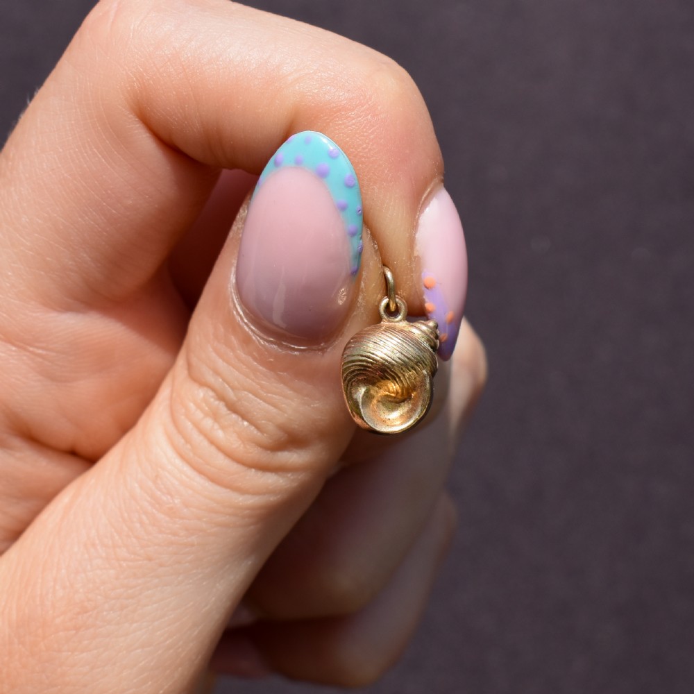 A small three-dimensional 9ct yellow gold seashell charm with ribbed texturing and a top suspension ring. View IV