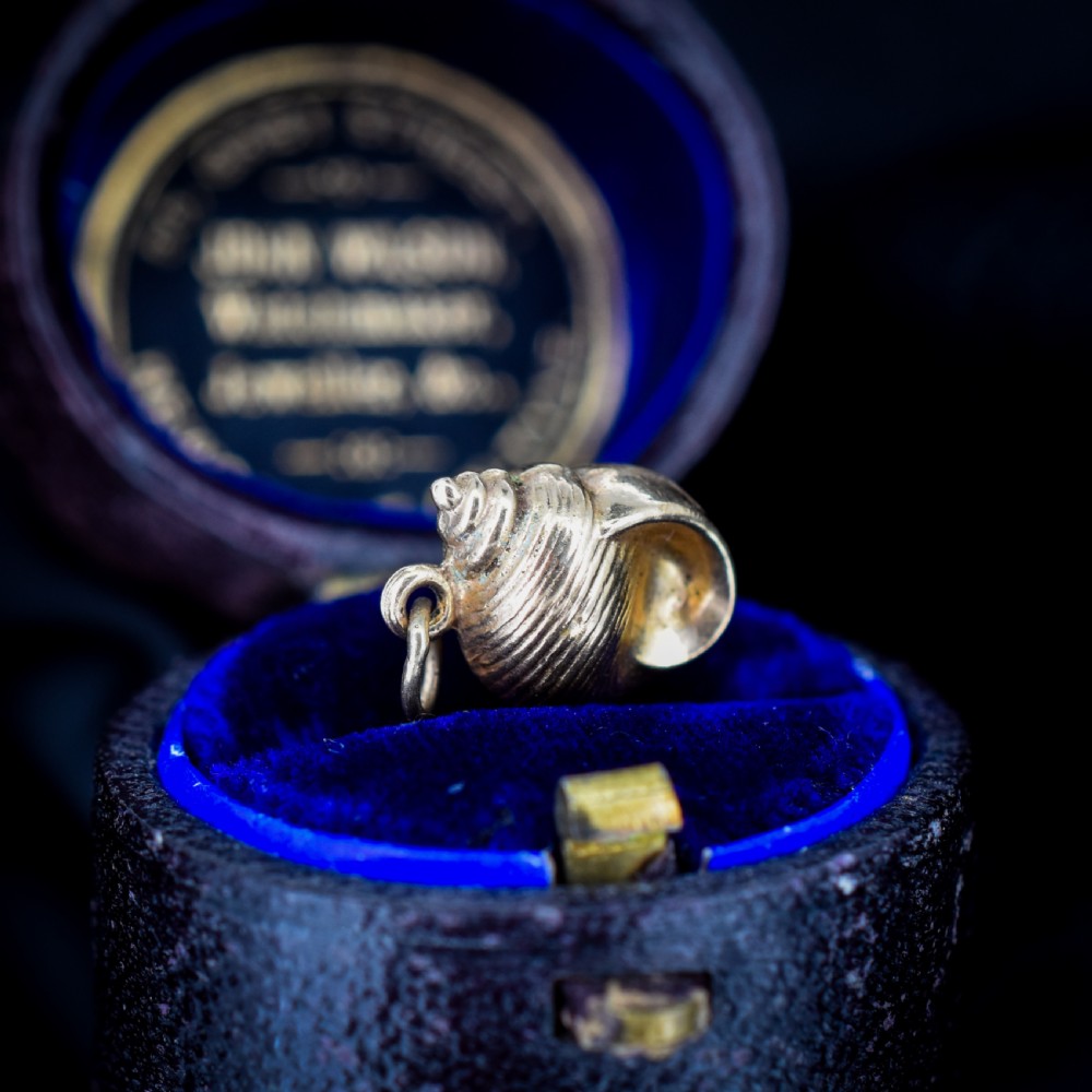 A small three-dimensional 9ct yellow gold seashell charm with ribbed texturing and a top suspension ring. View VI