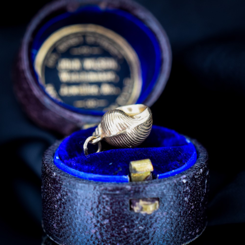 A small three-dimensional 9ct yellow gold seashell charm with ribbed texturing and a top suspension ring. View VII