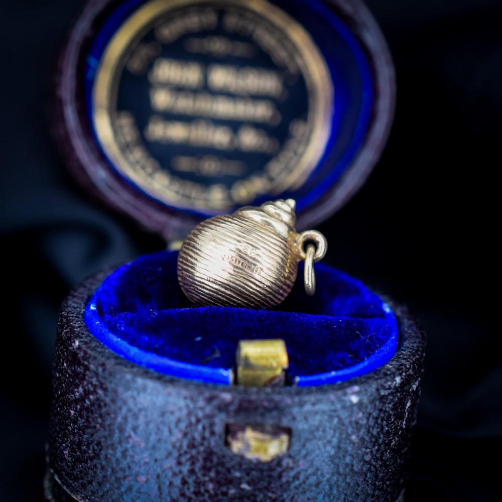 A small three-dimensional 9ct yellow gold seashell charm with ribbed texturing and a top suspension ring. View IX
