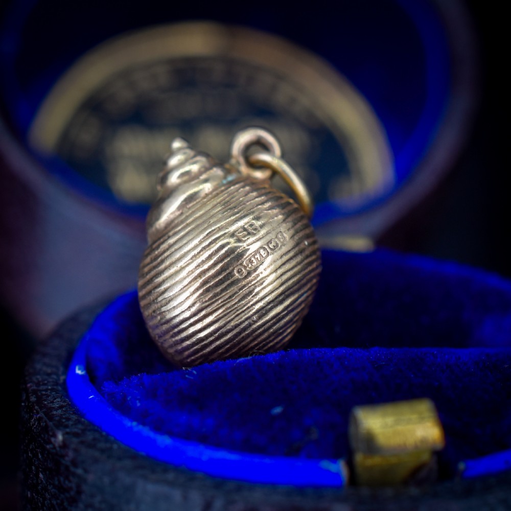 A small three-dimensional 9ct yellow gold seashell charm with ribbed texturing and a top suspension ring. View X