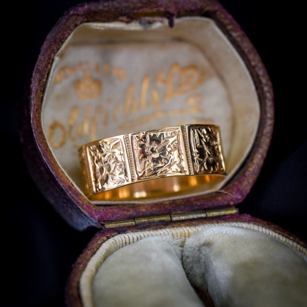 A wide 9ct yellow gold Victorian cigar band ring displaying carved square floral panels around the circumference. View VI