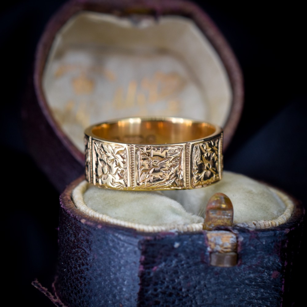 A wide 9ct yellow gold Victorian cigar band ring displaying carved square floral panels around the circumference. View VII