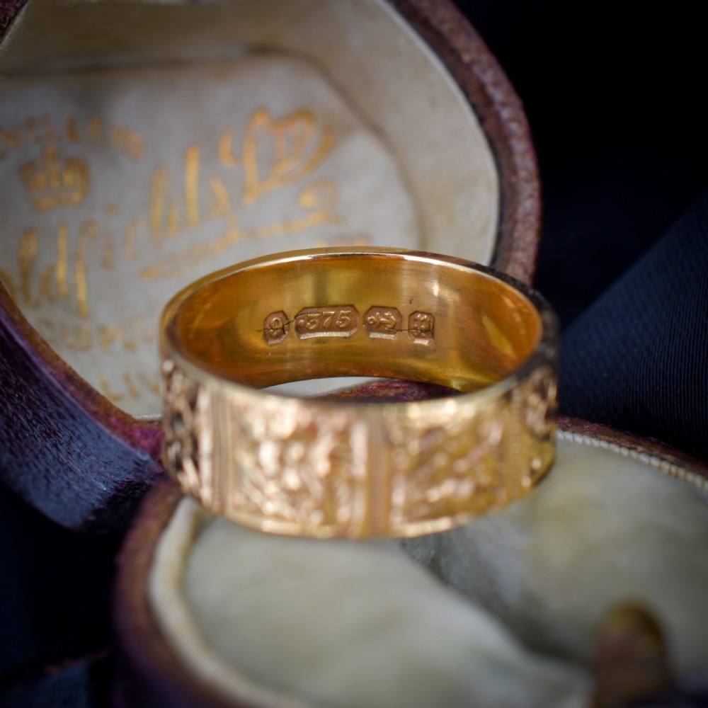 A wide 9ct yellow gold Victorian cigar band ring displaying carved square floral panels around the circumference. View VIII