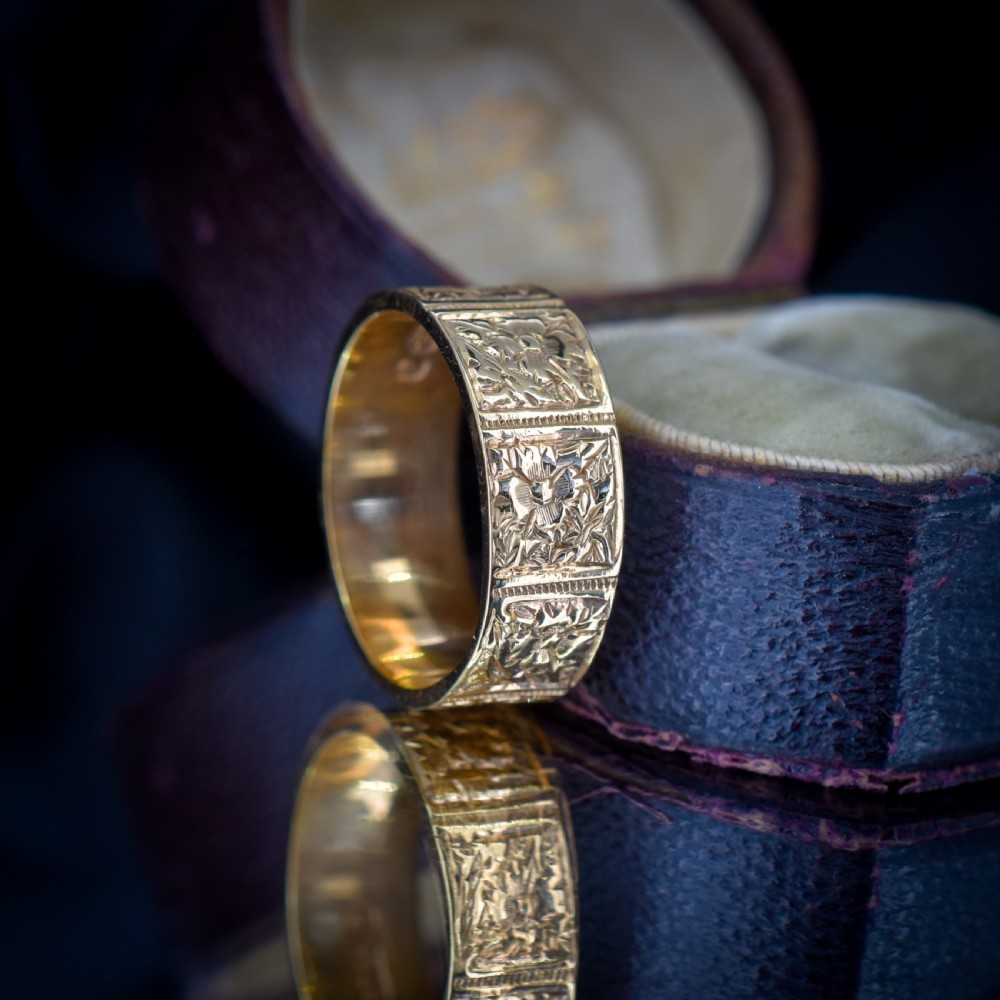 A wide 9ct yellow gold Victorian cigar band ring displaying carved square floral panels around the circumference. View XI