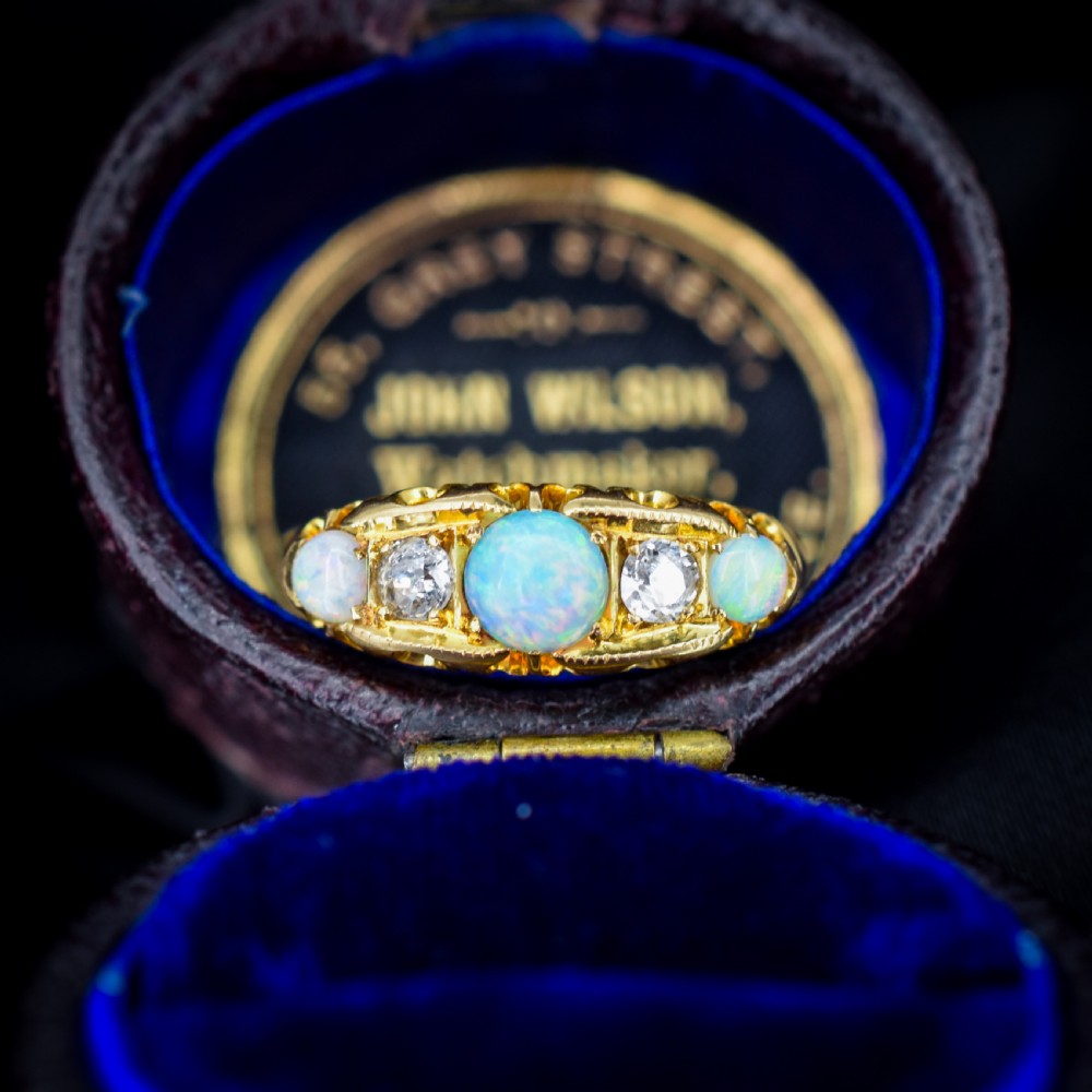 An Edwardian 18ct yellow gold boat ring set with three iridescent natural cabochon opals and two interspersed old-cut diamonds.