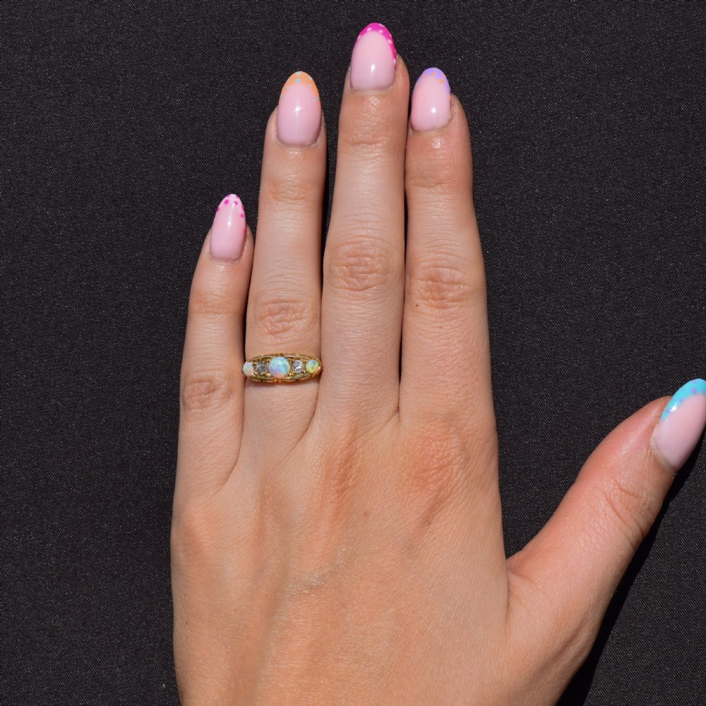 An Edwardian 18ct yellow gold boat ring set with three iridescent natural cabochon opals and two interspersed old-cut diamonds. View III