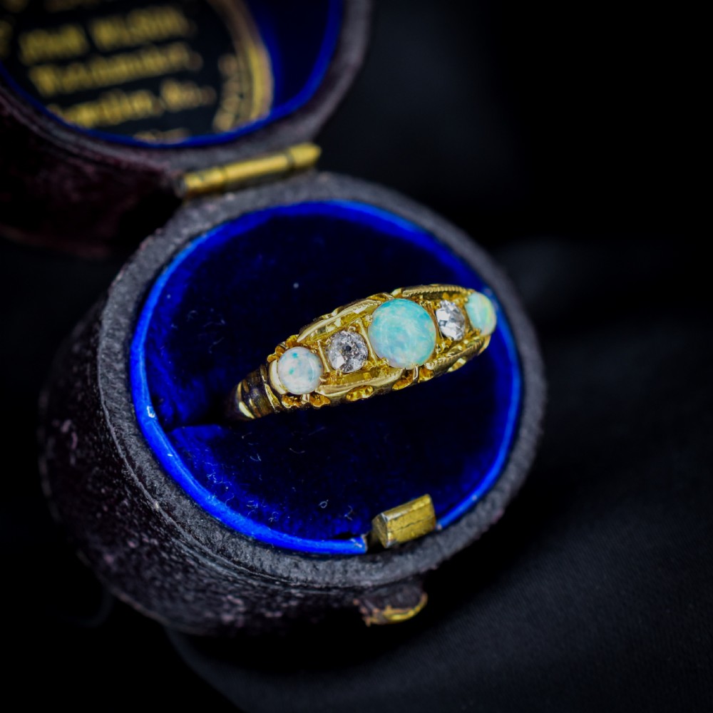 An Edwardian 18ct yellow gold boat ring set with three iridescent natural cabochon opals and two interspersed old-cut diamonds. View VI