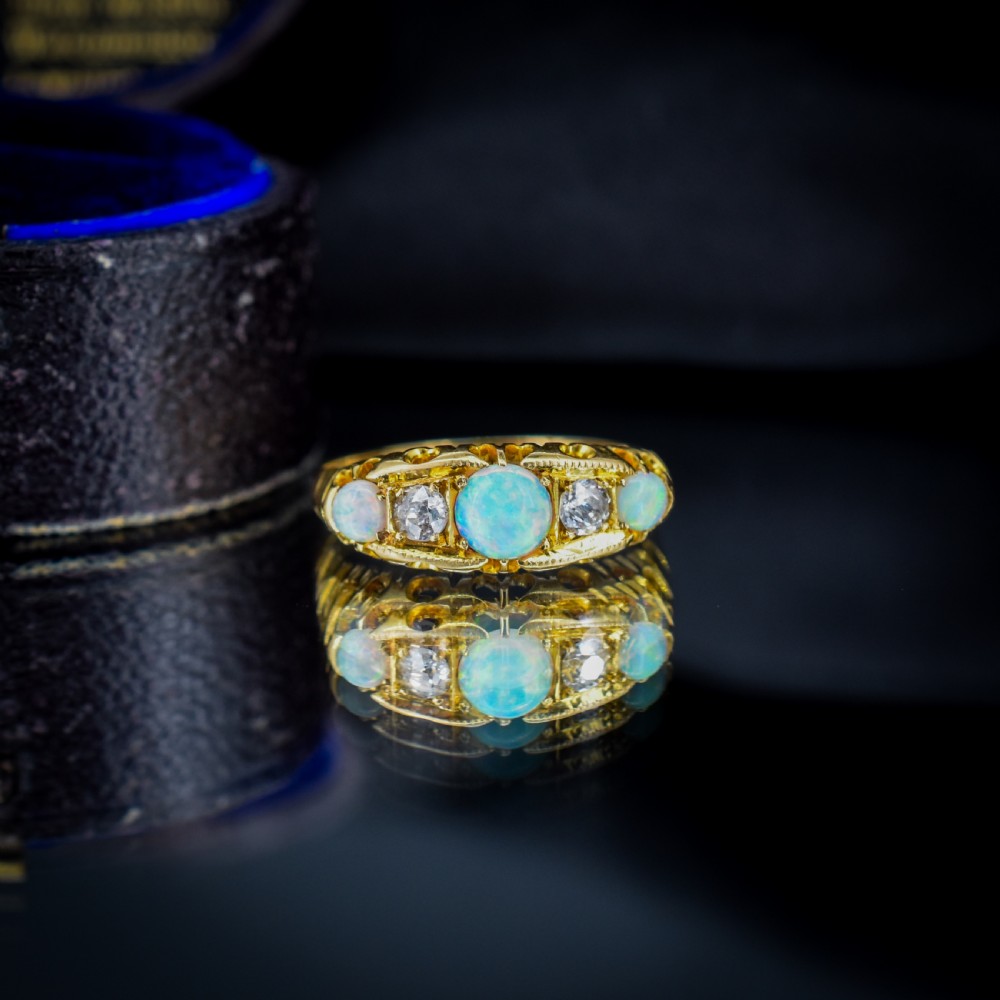 An Edwardian 18ct yellow gold boat ring set with three iridescent natural cabochon opals and two interspersed old-cut diamonds. View VII