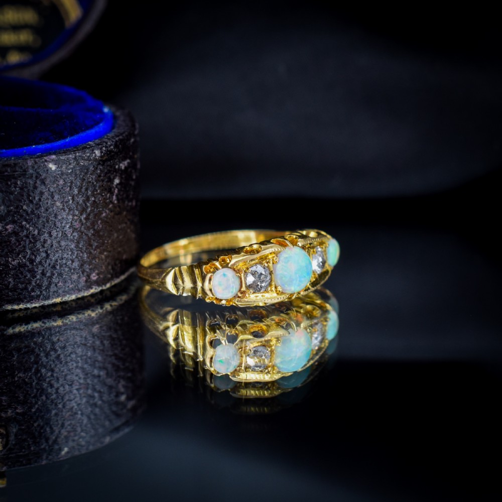 An Edwardian 18ct yellow gold boat ring set with three iridescent natural cabochon opals and two interspersed old-cut diamonds. View VIII