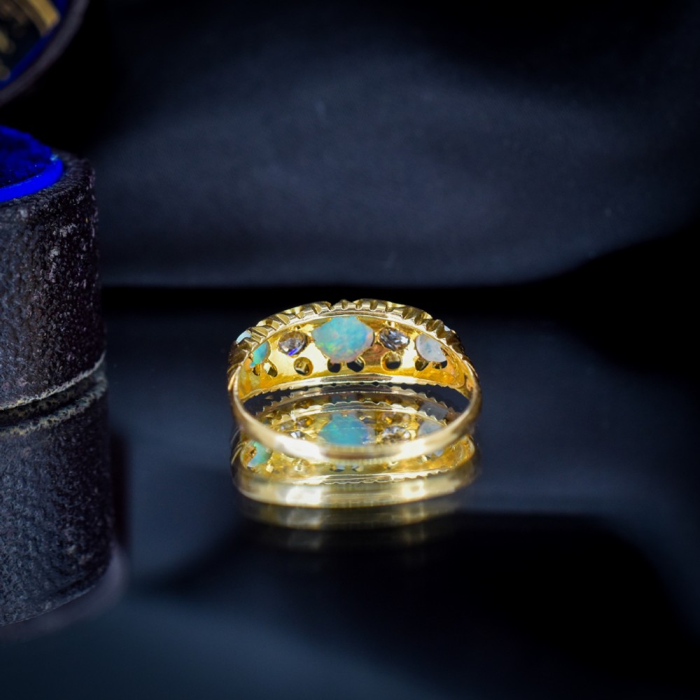 An Edwardian 18ct yellow gold boat ring set with three iridescent natural cabochon opals and two interspersed old-cut diamonds. View IX