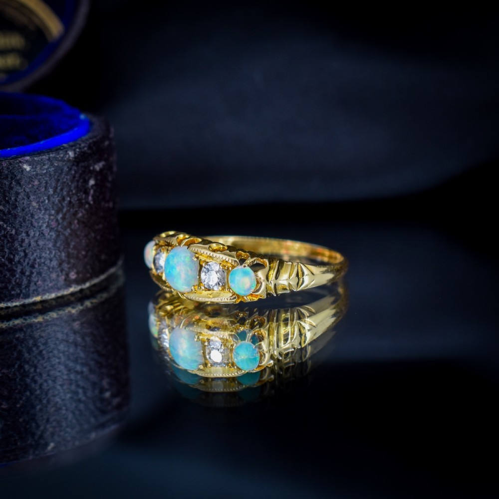 An Edwardian 18ct yellow gold boat ring set with three iridescent natural cabochon opals and two interspersed old-cut diamonds. View X